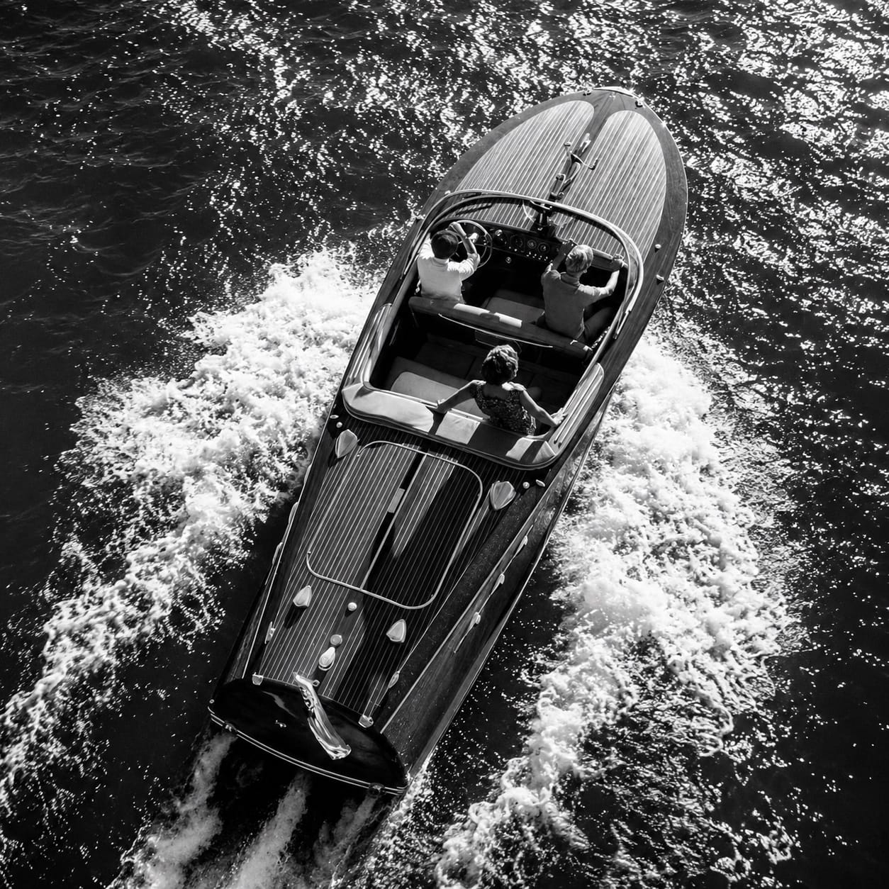 Aerial view of a classic wooden motor yacht under way with three people aboard
